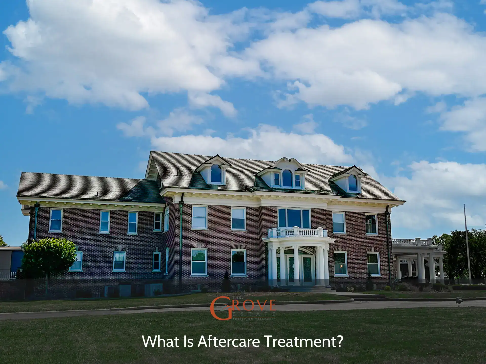 Historic brick building featuring large windows and a grand entrance, framed by lush greenery, representing a center for aftercare treatment.