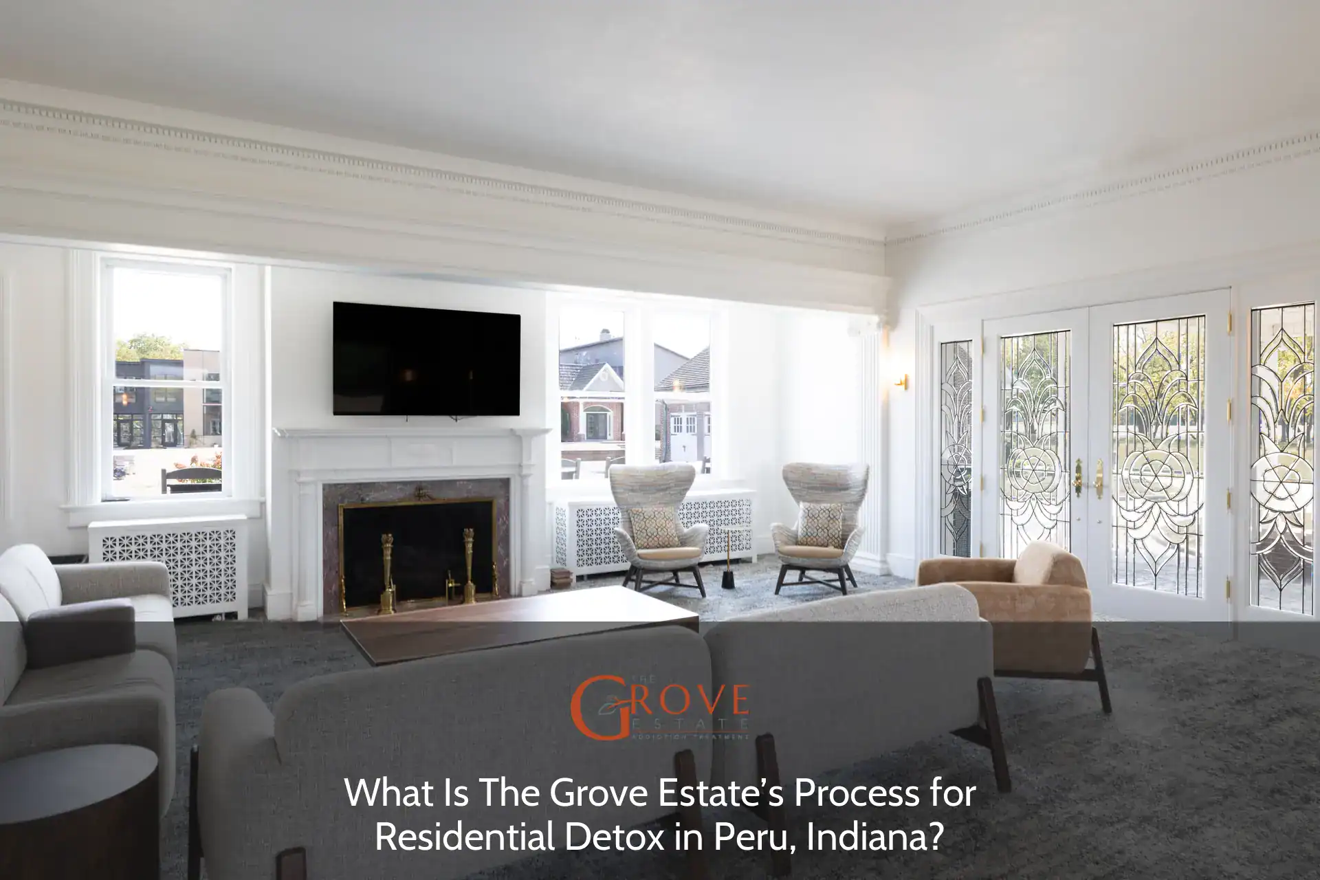 Spacious living area featuring plush seating, a modern TV, and elegant stained glass doors, showcasing the Grove Estate’s inviting atmosphere in Peru, Indiana.