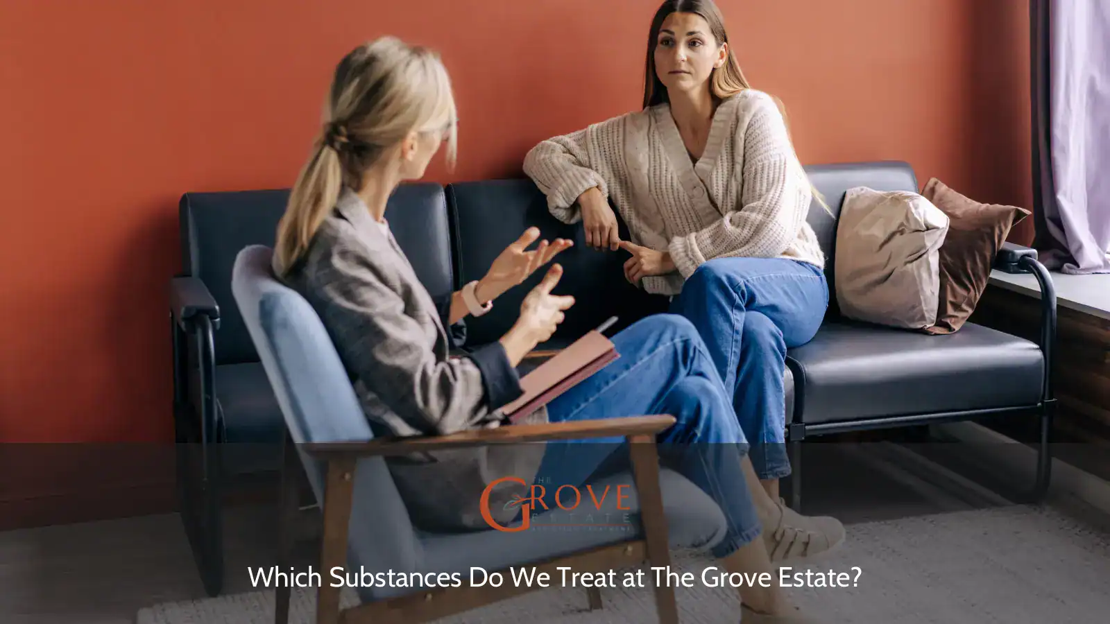 Two women engage in a conversation in a cozy setting, discussing treatment options at The Grove Estate, surrounded by warm tones and comfortable seating.